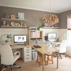 a home office with two computer desks and shelves