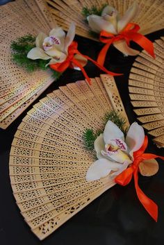 three fan shaped place mats with flowers on them and ribbons tied around the edges, sitting on a table