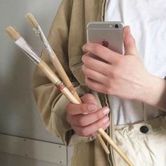 a person holding two brushes and an iphone