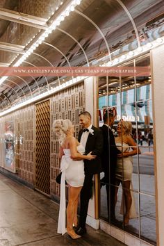 a man and woman standing next to each other in front of a wall with mirrors