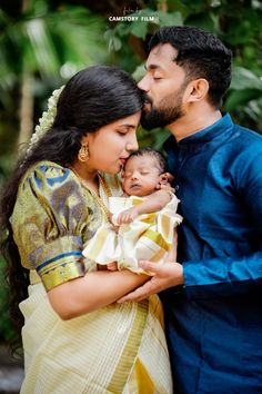 a man and woman holding a baby in their arms