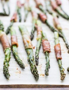 asparagus spears with bacon on them sitting on a cutting board