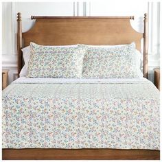 a bed with white and blue floral bedspread on it's headboard