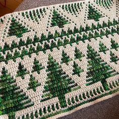 a green and white crocheted rug with trees on it