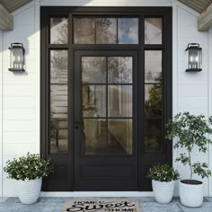 a black front door with two planters on the side and a welcome mat in front