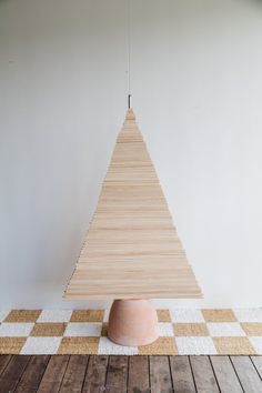 a wooden christmas tree sitting on top of a white and brown checkerboard floor