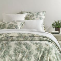 the comforter is made up with pine needles and white pillows on top of it