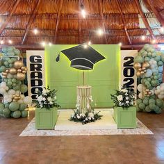 a stage set up with balloons, flowers and an umbrella for graduation party decorations on the dance floor