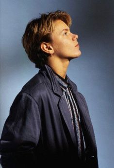 a young man wearing a suit and tie looking up into the sky with his hands in his pockets