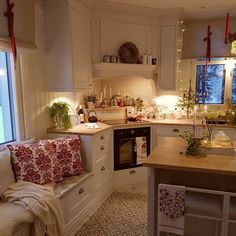 an instagram photo of a kitchen with white cabinets and pink pillows on the floor