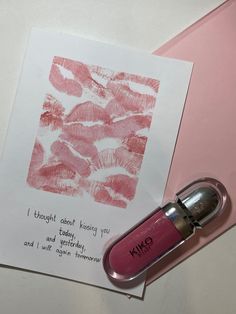 a pink lipstick bottle next to a piece of paper with writing on it