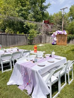 an outdoor table set up for a party in the grass with balloons and plates on it