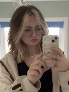 a woman taking a selfie in front of a mirror with her cell phone up to her ear