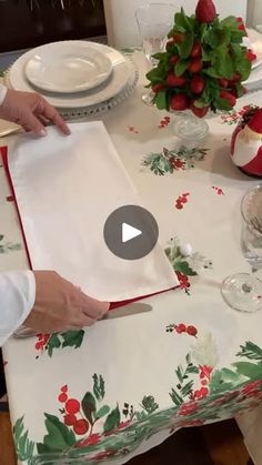 a person cutting up a piece of paper on top of a table with plates and glasses