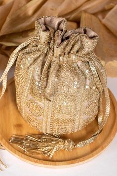 The Bella gold potli is a top seller at SaniyaCreations and the perfect example of the classy bling you love. This is a golden joy because to the delicate zari and sequin embroidery on net and the zari tissue lining. *Length: 8.5" *Base diameter: 7" *Handle drop: 5" (13 cm) *Material : Embroidered net fabric, poly satin lining, woven gold thread drawstrings and handle, layered cutdana tassels. Accessibility : Earrings, rings, bracelets, and other jewellery items can be carried in this case. Coin Bridal Clothing, Potli Bag, Potli Bags, Net Bag, Wedding Bag, Gold Embroidery, Sequins Embroidery, Silk Embroidery, Online Bags