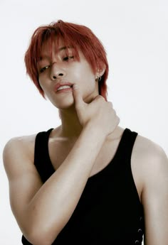 a woman with red hair and piercings posing for a photo in front of a white background