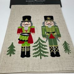 two nutcrackers in green and red are standing next to each other with pine trees