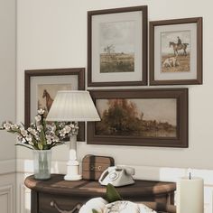 a living room with pictures on the wall and flowers in vases next to it