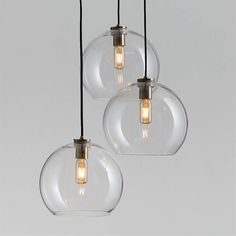 three clear glass globe pendant lights hanging from a ceiling