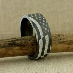 an american flag ring sitting on top of a piece of wood next to a wooden stick