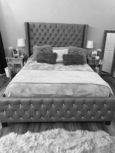 black and white photograph of a bedroom with a bed, nightstands, and mirror