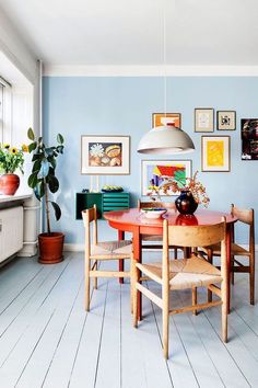 a dining room with blue walls and pictures on the wall above the dinning table