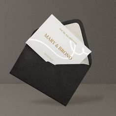 a black envelope with a white business card inside and gold foil lettering on the front