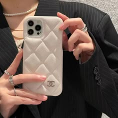 a woman in a suit holding up her white iphone case with the initials on it