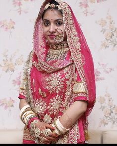 a woman in a red and gold bridal outfit with her hands on her hips