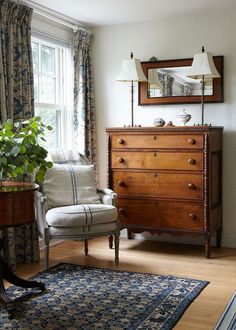 a living room filled with furniture and a large mirror on top of a dresser next to a window