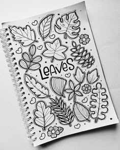 a notebook with leaves on it and the words leaves written in black ink next to an open spiral notebook