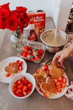 someone is cutting up some heart shaped pancakes with strawberries on the plate next to them