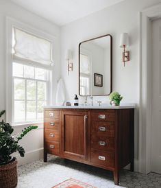 a bathroom with a sink, mirror and potted plant in the window sill