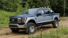 a large gray truck driving down a dirt road