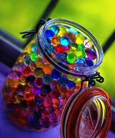 a jar filled with lots of different colored beads sitting on top of a window sill