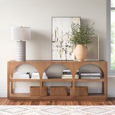 a wooden shelf with books and baskets on it in front of a window, next to a lamp