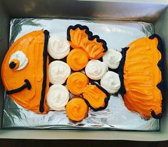 an orange and white cake in a box with decorations on the side that looks like a fish