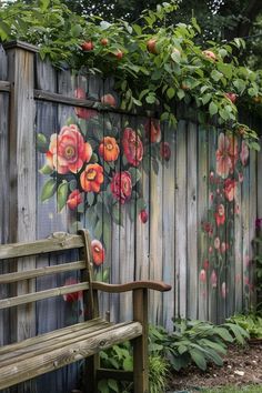 a wooden bench sitting in front of a fence with flowers painted on the wall behind it