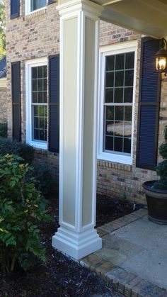 a white column in front of a brick house