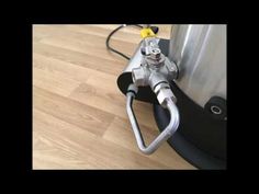 a silver and black vacuum sitting on top of a wooden floor next to a metal tank