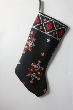 an embroidered christmas stocking hanging from a hook on a white wall with snowflakes