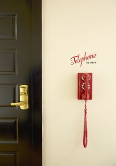 a red phone is hanging on the wall next to a door with a sign that says telephone to work