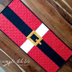 a red, white and black quilted placemat on a wooden floor with wood planks