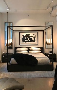 a bedroom with a four poster bed and white sheets, black furniture and artwork on the wall