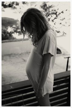 a black and white photo of a woman with her hands in her pockets looking down