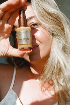 a woman holding up a bottle of mineral oil