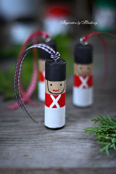 two small wooden nutcrackers decorated with red and white paint, tied to string