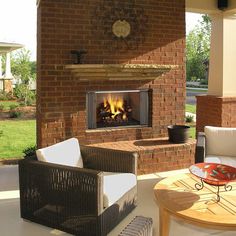 an outdoor fireplace with wicker furniture on the patio