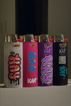 four different colored lighters with graffiti on them