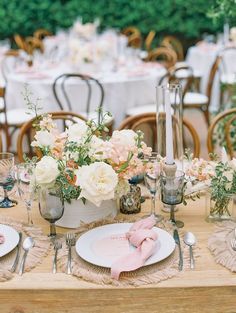 the table is set with white and pink flowers, gold rimmed glasses, and silverware